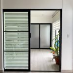 Puertas de aluminio negro y vidrio laminado tipo pocket para separar espacios.