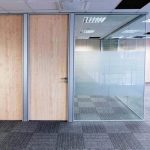 Sistema de divisiones con channel de aluminio y vidrio laminado, con puertas ciegas de apertura automática.